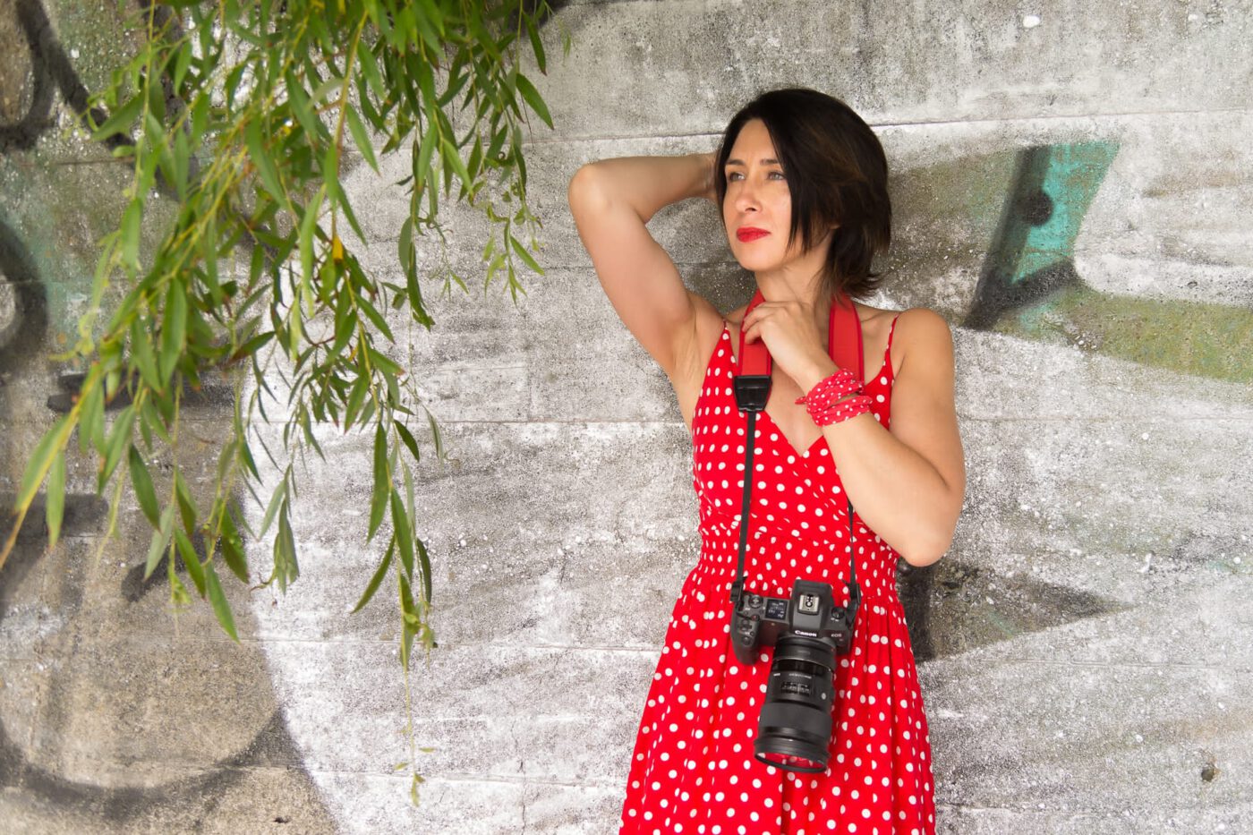 kobieta z aparatem fotograficznym w czerwonej sukience oparta o falohron
